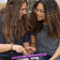 Two girls looking at a Via Pro and smiling