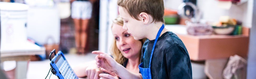 Teacher assisting student with AAC device in art class